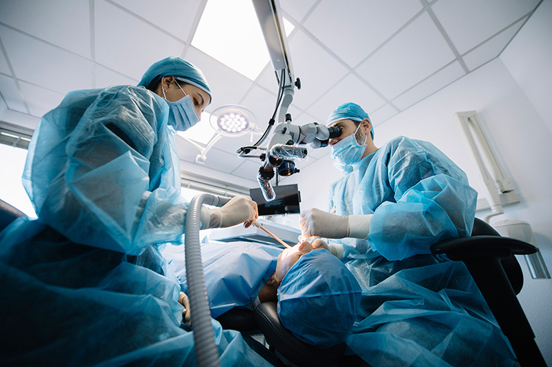 An oral surgeon and a dental assistant performing surgery on a patient