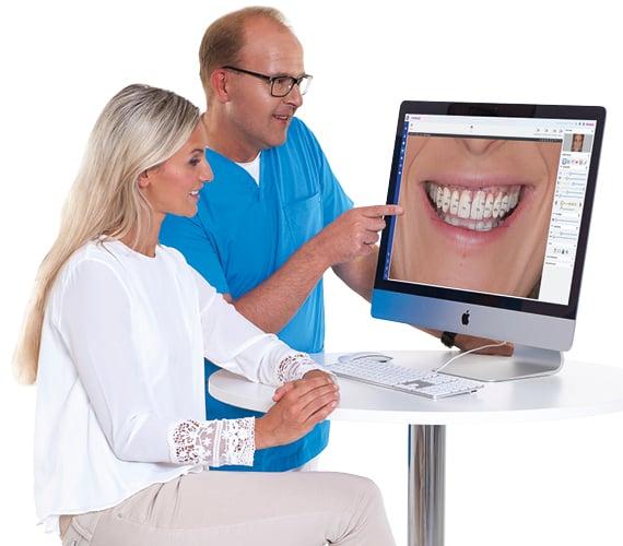 Dentist and assistant review a computer screen showing a close-up of teeth.
