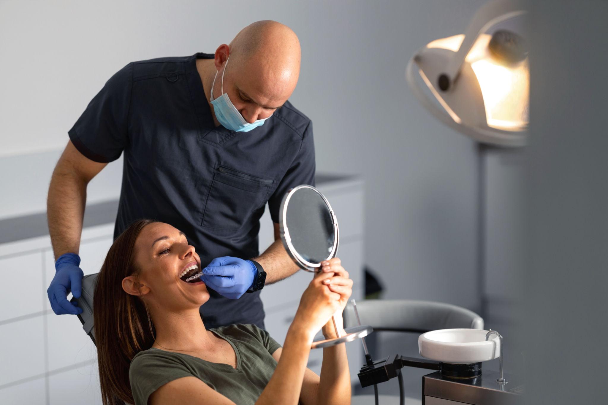 Dentist wearing a mask and gloves examining a patient's mouth in a dental clinic.